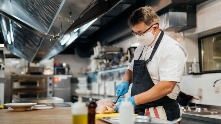 Professional kitchen cleaning supplies including sanitizers, degreasers, and microfiber cloths arranged on stainless steel surface